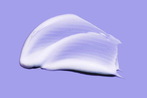 Foto maschera di crema cosmetica bianca macchia di consistenza isolata su sfondo viola chiaro