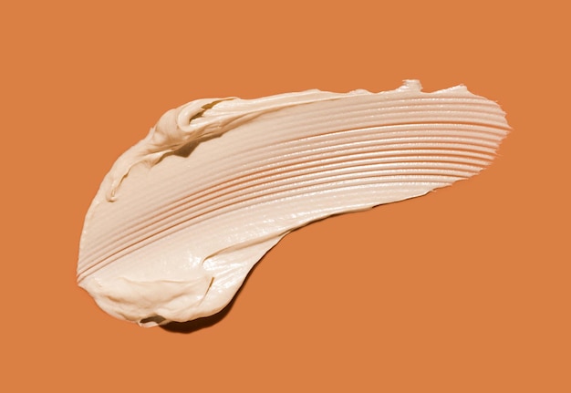 Фото Косметическая белая кремовая бальзамная маска с текстурой, изолированная на оранжевом фоне