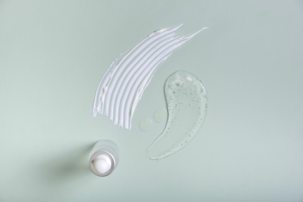 Cosmetic white and transparetn smears and pipette bottle on colored background top view