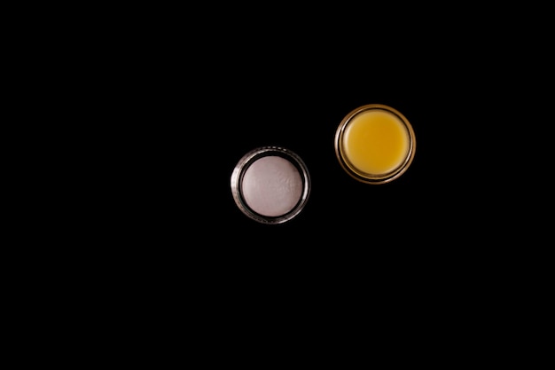 Cosmetic yellow balm from other manufacturers for daily skin care on a black background. Skin care products concept