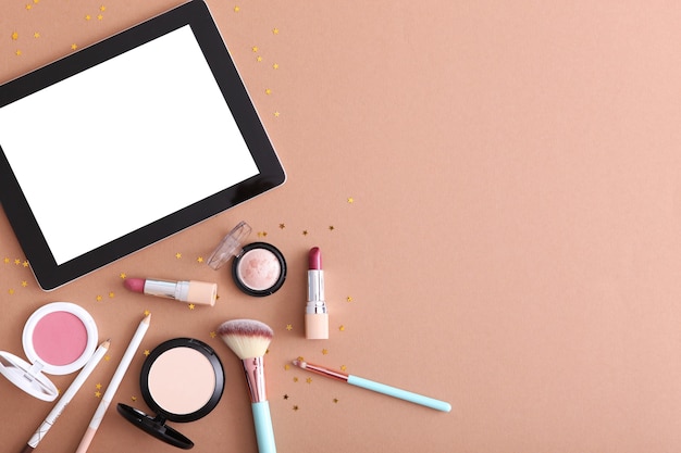 Cosmetica en moderne tablet op een gekleurde achtergrond bovenaanzicht