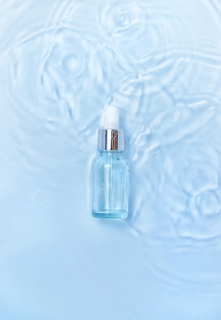 Cosmetica in een fles in water, huidhydratatieconcept. Hyaluronzuur. Selectieve aandacht. Natuur.