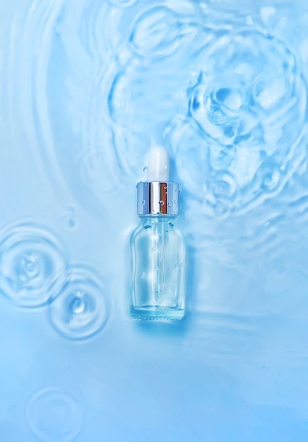 Cosmetica in een fles in water, huidhydratatieconcept. Hyaluronzuur. Selectieve aandacht. Natuur.