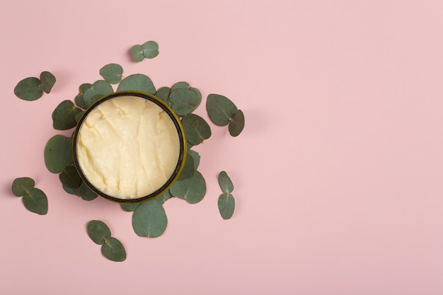 Cosmetica pot met eucalyptus bladeren op roze achtergrond