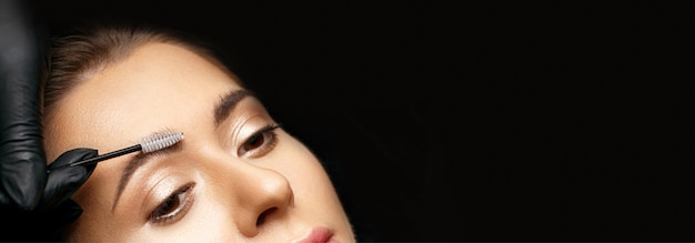 Photo cosmetician brushing brows with small brush before coloration