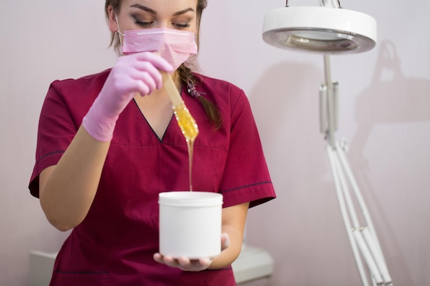 Cosmetician takes the sugar paste from the jar Shugaring Sugar paste