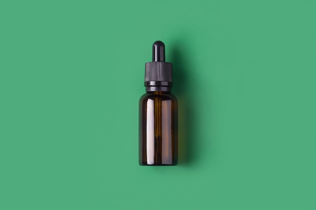 Cosmetics bottle on green background top view