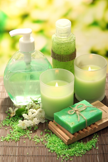 Cosmetics bottles and natural handmade soap on green background