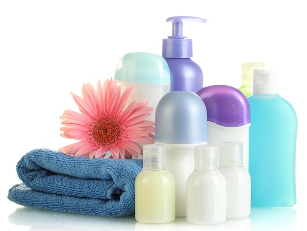 Cosmetics bottles with towel and flower isolated on white