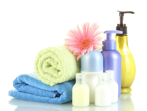 Cosmetics bottles with towels and flower isolated on white