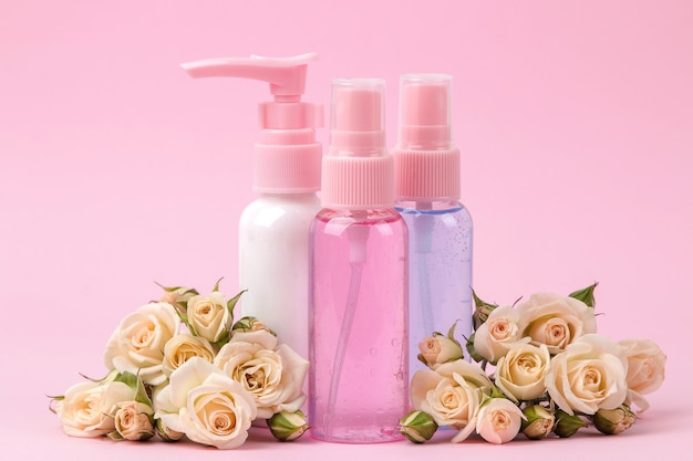 Cosmetics for face and body in pink bottles with fresh roses on a delicate pink background. cream and lotion. spa.