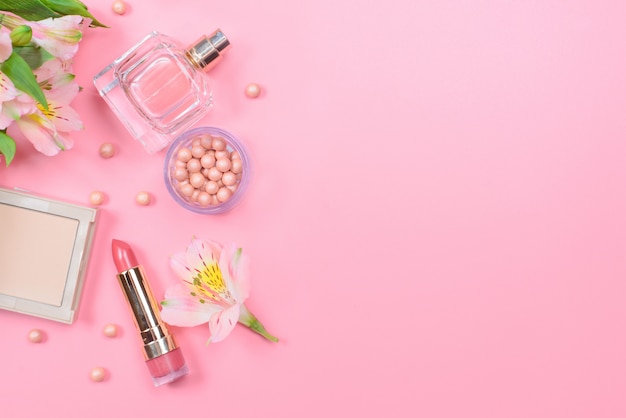 Cosmetics and flowers on a pink table with copyspace