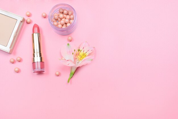 Foto cosmetici e fiori su una tavola rosa con copyspace