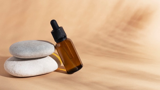 Cosmetics oil or essence in glass bottle with shadows on beige background