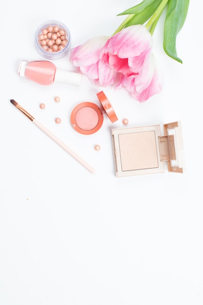 Cosmetics and pink tulips on a white surface