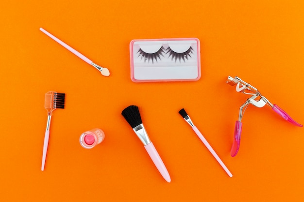 Cosmetics set for women isolated on orange paper background