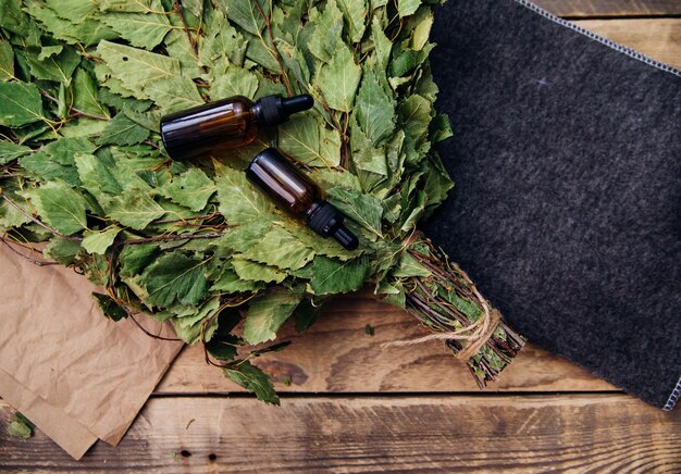 Cosmetics for spa treatments and baths on a wooden table with a birch broom