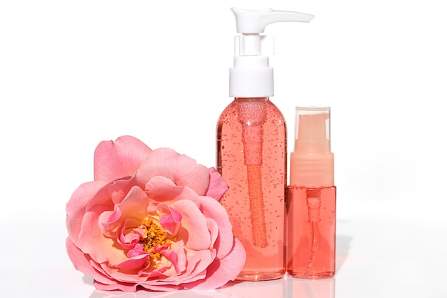 Cosmetici con estratto di rosa. gel e tonico di colore rosa con estratto di rosa in una bottiglia di plastica e spugna grande fiore rosa rosa