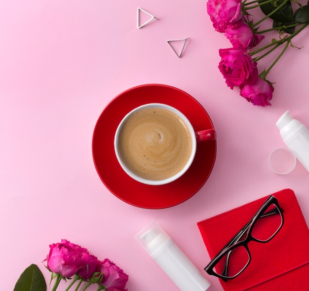 Cosmetisch huidverzorgingsproduct, notebook, koffie en bloemen op roze