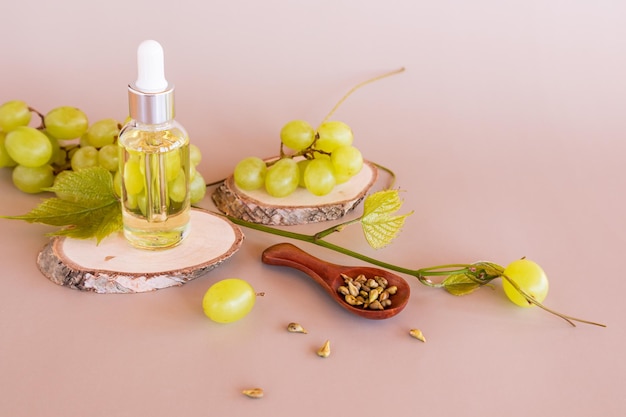 Cosmetisch natuurproduct op basis van druivenpitolie in een glazen flesje met een pipet tegen de achtergrond van rijpe druiven