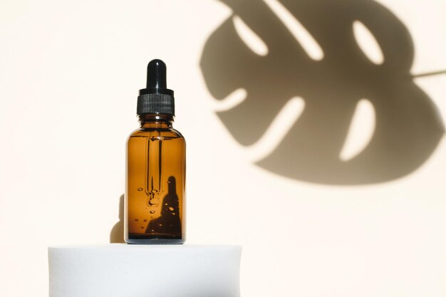 Cosmetisch product voor dames in een amberkleurige fles met een huidverzorgingspipet op het podium en schaduw
