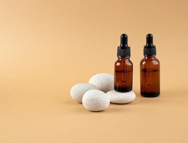 Cosmetisch product voor gezichtsverzorging Twee flessen gevuld met etherische olie-essence serum voor huidverzorging voor vrouwen op een achtergrond met stenen