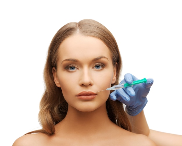 cosmetische chirurgie concept - vrouw gezicht en schoonheidsspecialiste hand met spuit