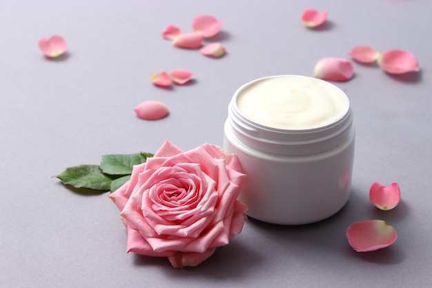 Cosmetische crème en bloemen op een gekleurde close-up als achtergrond