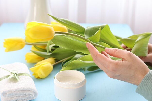 Cosmetische crème en gele tulpen op tafel