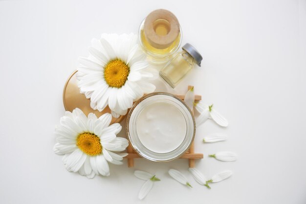 Cosmetische crème en kamille bloemen op witte achtergrond