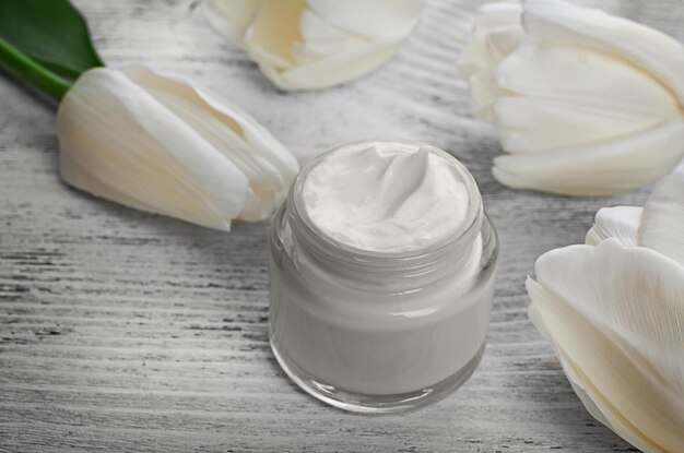 Cosmetische crème met tulpen op witte houten achtergrond