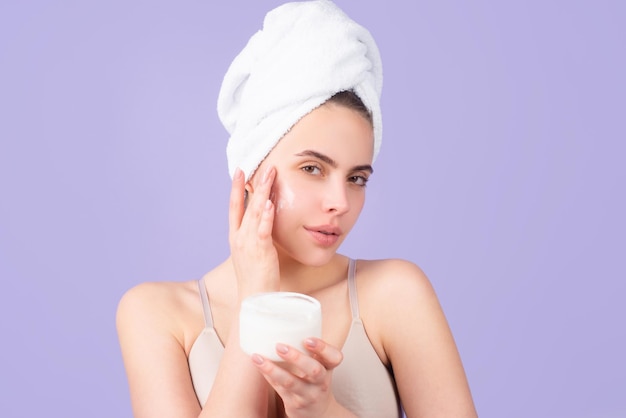 Cosmetische crème op het gezicht van de vrouw met een schone, zachte huid lichaamsverzorging vrouw met een handdoek die crème op de huid aanbrengt