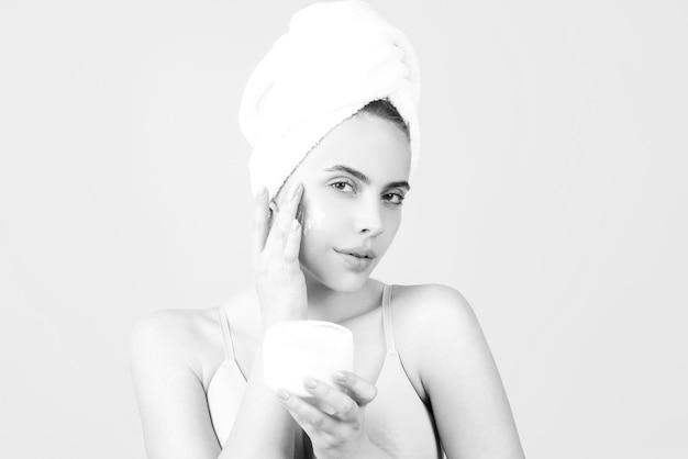Cosmetische crème op het gezicht van de vrouw met een schone, zachte huid lichaamsverzorging vrouw met een handdoek die crème op de huid aanbrengt