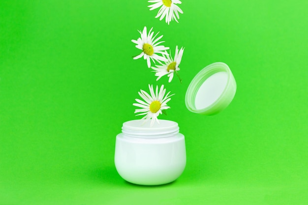 Cosmetische crèmepot met open deksel op groene achtergrond. Supplement fles Jar verpakking Mockup. Creatieve lente bloei lay-out.