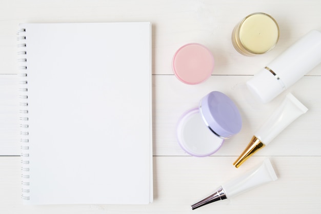 Cosmetische en huidverzorgingsproducten en notebook op witte houten tafel