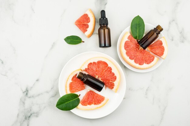 Cosmetische en medische flessen met grapefruitextract op witte borden met fruitslijm en bladeren. bovenaanzicht.