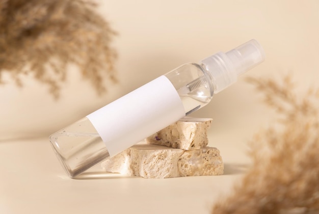 Cosmetische fles met blanco etiket op stenen in de buurt van pampagras close-up mockup