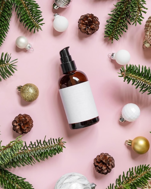 Cosmetische fles met één pomp in de buurt van kerstversiering, dennentakken en dennenappels op roze mockup