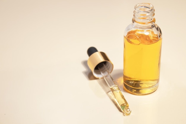 Cosmetische fles met pipet met vloeibaar serum en schaduwen op beige achtergrond