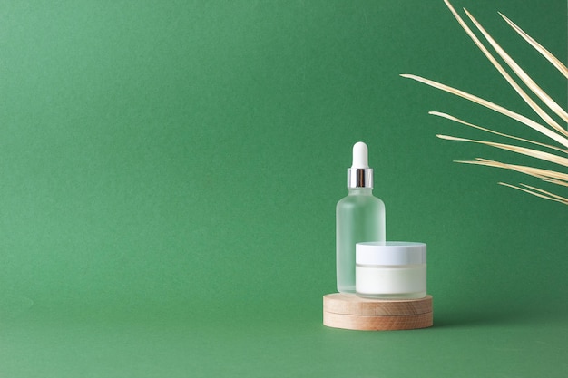 Cosmetische huidverzorgingsproducten met houten podium en palmblad op groene achtergrond Close Up copy space