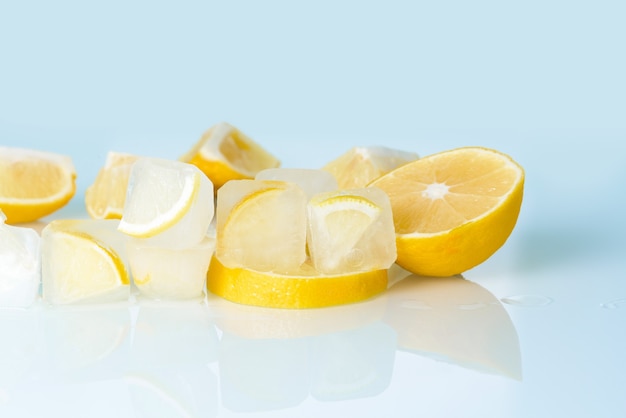 Cosmetische ijsblokjes met citroen en vitamine C voor huidverzorging op een blauwe lichte achtergrond, natuurlijke biologische ingrediënten voor thuiszorg, detox. plaats voor tekst.