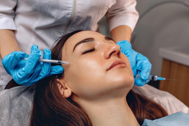 Cosmetische ingreep close-up. De handen van de schoonheidsspecialist houden spuiten vast. Het doen van de anti-aging procedure.