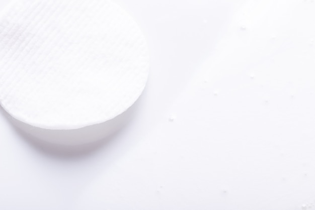 Cosmetische katoenen schijf en witte crème, gestructureerde achtergrond