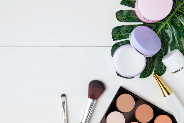 Cosmetische make-up en huidverzorgingsproduct en bladeren op witte houten tafel