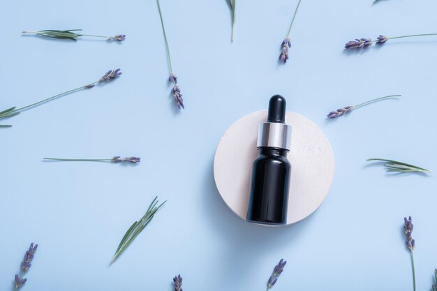 Cosmetische olie of serum in druppelflesje met lavendelbloemen op gekleurde achtergrond bovenaanzicht