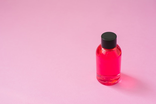 Cosmetische product fles roze met zwarte dop voor lichaamsverzorging cosmetica of haar op roze achtergrond.