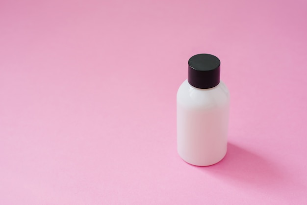 Cosmetische product fles wit met zwarte dop voor lichaamsverzorging cosmetica of haar op roze copyspace