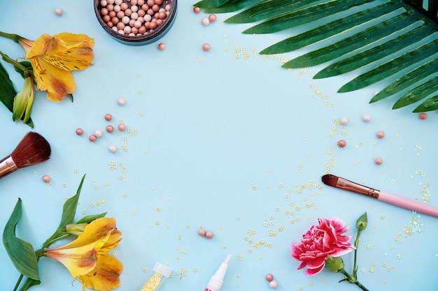 Cosmetische producten accessoires borstels voor make-up en poeder Bloemen decoraties Schoonheid concept Bovenaanzicht kopie ruimte blauwe achtergrond Hoge kwaliteit foto