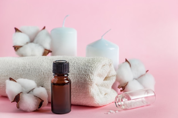 Cosmetische producten voor spa en aromatherapie kaarsen zeezout handdoek en bloemen op roze achtergrond