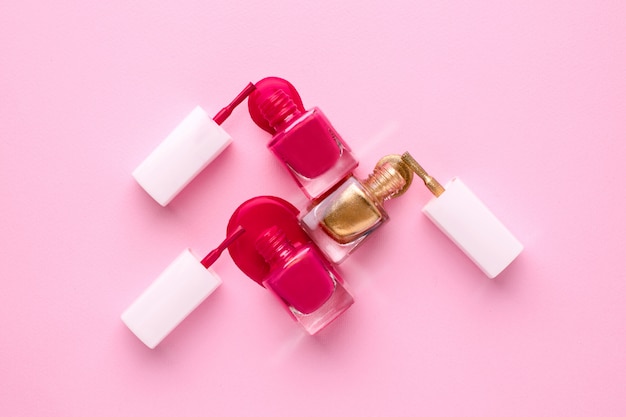 Cosmetische roze en gouden nagellakken op roze